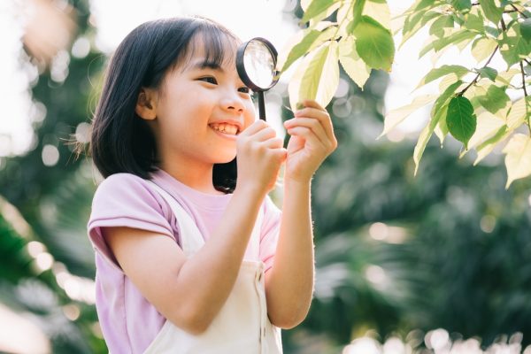 Asian,Little,Girl,Is,Using,Magnifying,Glass,To,Play,In