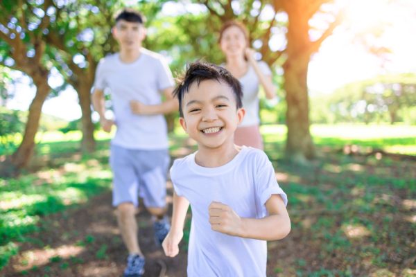 Happy,Boy,Jogging,With,Parents,In,The,City,Park